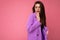 Young shocked amazed brunette woman beautiful fashionable wearing trendy purple jacket isolated on pink background with