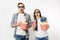 Young shocked couple, woman and man in 3d glasses watching movie film on date, holding bucket of popcorn, plastic cup of