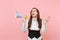 Young shocked exhausted business woman in suit, glasses looking up holding megaphone and mobile phone on pink