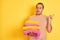 Young shopkeeper man holding folded towels standing over isolated yellow background very happy pointing with hand and finger to