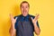 Young shopkeeper man wearing apron standing over isolated yellow background celebrating crazy and amazed for success with arms