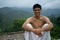 Young shredded man sitting wearing a dhoti and glasses with blurred mountains in the background