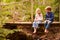 Young siblings sitting on a bridge in a forest