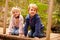 Young siblings sitting on a bridge in a forest, portrait