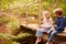 Young siblings sitting on wooden bridge in a forest