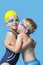 Young siblings in swimwear embracing and kissing over blue background