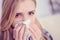 Young sick Caucasian woman sneeze at home on the sofa with a cold. Girl Used tissue paper blowing her nose. Medical and
