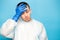 Young sick doctor man touching his head with hand in gloves isolated on blue