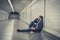 Young sick man lost suffering depression sitting on ground street subway tunnel