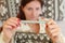 Young sick woman laying in bed, holding classic mercury thermometer in front of her