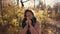 Young sick woman is sneezing standing in park in autumn day, using handkerchief