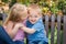 Young Sister and Brother Snuggle On a Bench At The Park