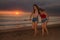 Young sisters or Asian Chinese girl at sunset beach with her best friend having fun enjoying Summer holidays trip together walkin