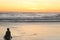 A young sitting boy playing and enjoying alone the wet and reflecting sand and looks to the ocean and sky at sunset time at Parang