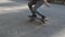 Young skateboarder legs riding skateboard at park and doing flip trick, kickflip drop
