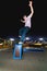 Young skater doing trick slide on railing in skatepark at night