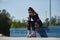 Young skater female sitting on a ledge in a skatepark with a glass bottle of water and smartphone. Roller blader person wearing