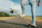 Young skater in white sneakers standing on a skateboard on the road