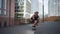 Young skilful skater performing with longboard at sunset in urban city street