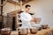 Young skillful baker putting bowl with flour on kitchen scale