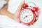 Young sleeping woman and alarm clock in bedroom