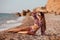 Young slender girl in bikini swimwear sunbathing on the shore by sea. Beautiful model enjoying life on beach