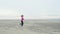 Young, slender girl in a pink t-shirt and black leggings runs along a deserted sandy beach. Slow motion outdoor training on a clou