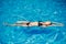 Young slender woman in a black bikini swimsuit relaxes on the surface of the water in the pool