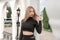 Young slender woman with blonde hair in black tight-fitting outfit outdoors. Portrait of girl in crop top in the city