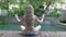 The young slender woman with long hair meditates on the edge of the pool in the tropical resort