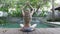 The young slender woman with long hair meditates on the edge of the pool in the tropical resort