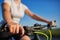 Young slender woman sitting on bicycle, holding handlebars with hands. Woman in the park sunset lighting.