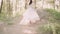 Young slim and attractive girl in elegant white vintage dress with a long fluttering train and flying dark wavy hair in