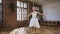 Young slim ballerina dressed in white tutu trains gracefully in pointe ballet shoes in ballroom. Graceful ballerina