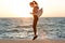 Young slim brunette woman in sport wear jumping on seaside