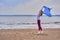 Young slim brunette woman in sportswear doing sport dancing with a blue scarf. A woman is engaged on the sandy shore of a large ri