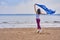 Young slim brunette woman in sportswear doing sport dancing with a blue scarf. A woman is engaged on the sandy shore of a large ri