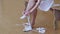 Young slim girl ballerina puts on her feet pointe shoes sitting on the bench in studio. Legs close-up.