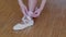 Young slim girl ballerina puts on her feet pointe shoes sitting on the bench in studio. Legs close-up.