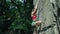 Young slim muscular woman rockclimber climbing on tough sport route, hunging on carabiner and trying to attach the rope