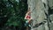 Young slim muscular woman rockclimber climbing on tough sport route, reaching and gripping holds and trying to attach