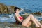 Young slim pretty lady wear bikini lying on sea rocks