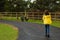 Young slim teenager girl in yellow jacket in walking on a footpath in a zoo park. Outdoor acitivity