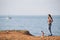 Young slim woman animal trainer in paid shirt and jeans with standing on hinder legs little chihuahua dog on sea shore with yacht