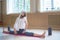Young slim woman with blonde hair sitting on the yoga mat in horizontal split - dance studio