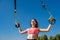 Young slim  woman doing suspension training with fitness straps outdoors near the lake at daytime. Healthy lifestyle