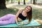 Young slim woman having snack after working out outdoors in the park. Sitting on the grass, eating juicy apple on fresh air