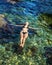 Young slim woman lies on surface of transparent seawater