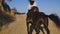 Young slim woman mounting horse and purebred animal galloping with rider away in slow motion. Wide shot back view of