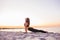 Young slim yogi woman doing Urdhva Mukha Svanasana or Upward Facing Dog Pose against sunset on the beach. Healhy lifestyle concept